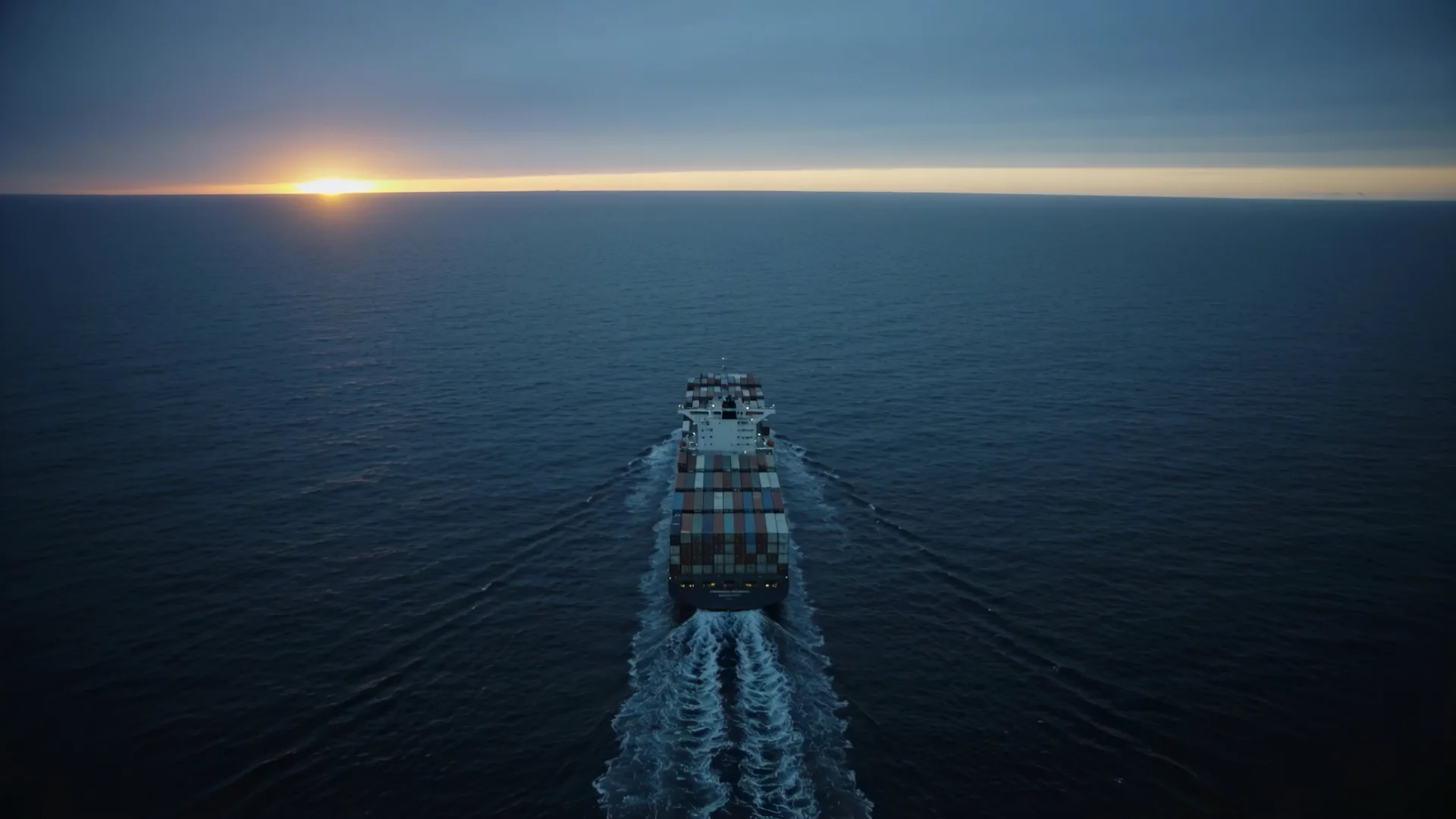 A Throne Worldwide container vessel underway toward the sunset horizon.